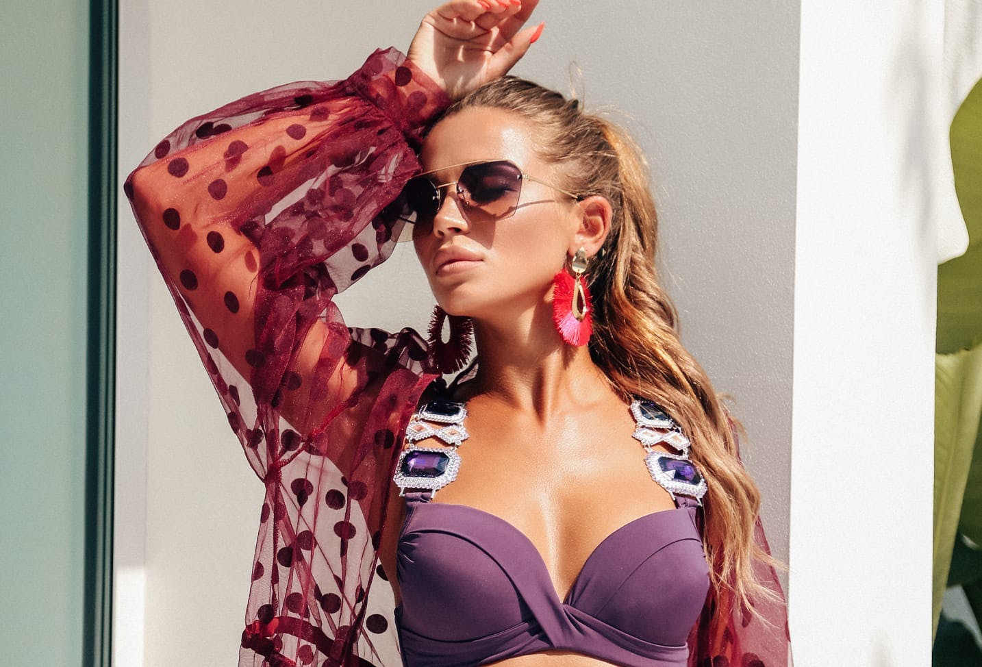 a brunette woman in a purple swimsuit and sunglasses