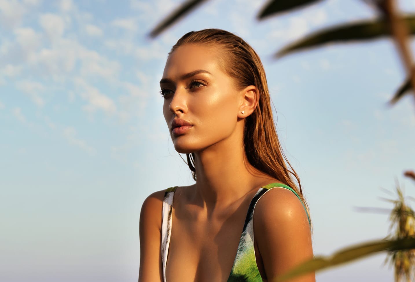 brunette woman with wet hair in a green swimsuit