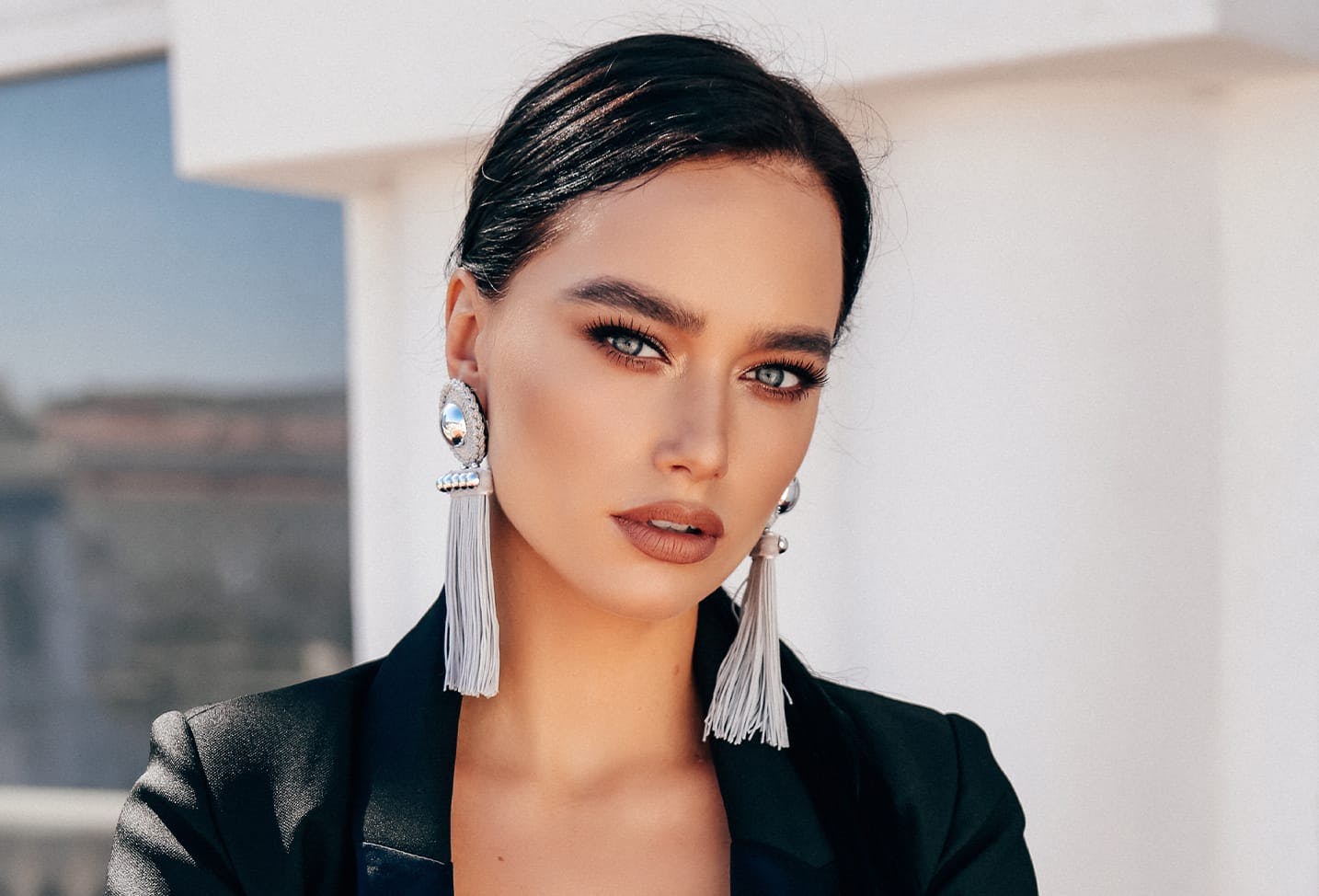 woman with black hair, a black blazer, wearing long silver earrings
