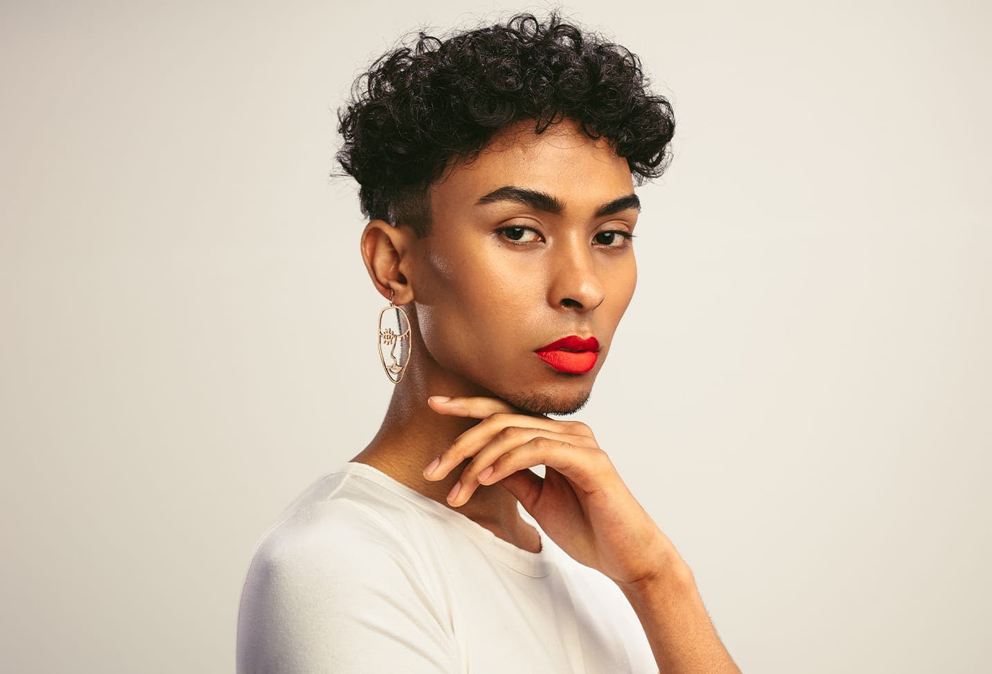 model with dark short curly hair with gold earring and red lipstick