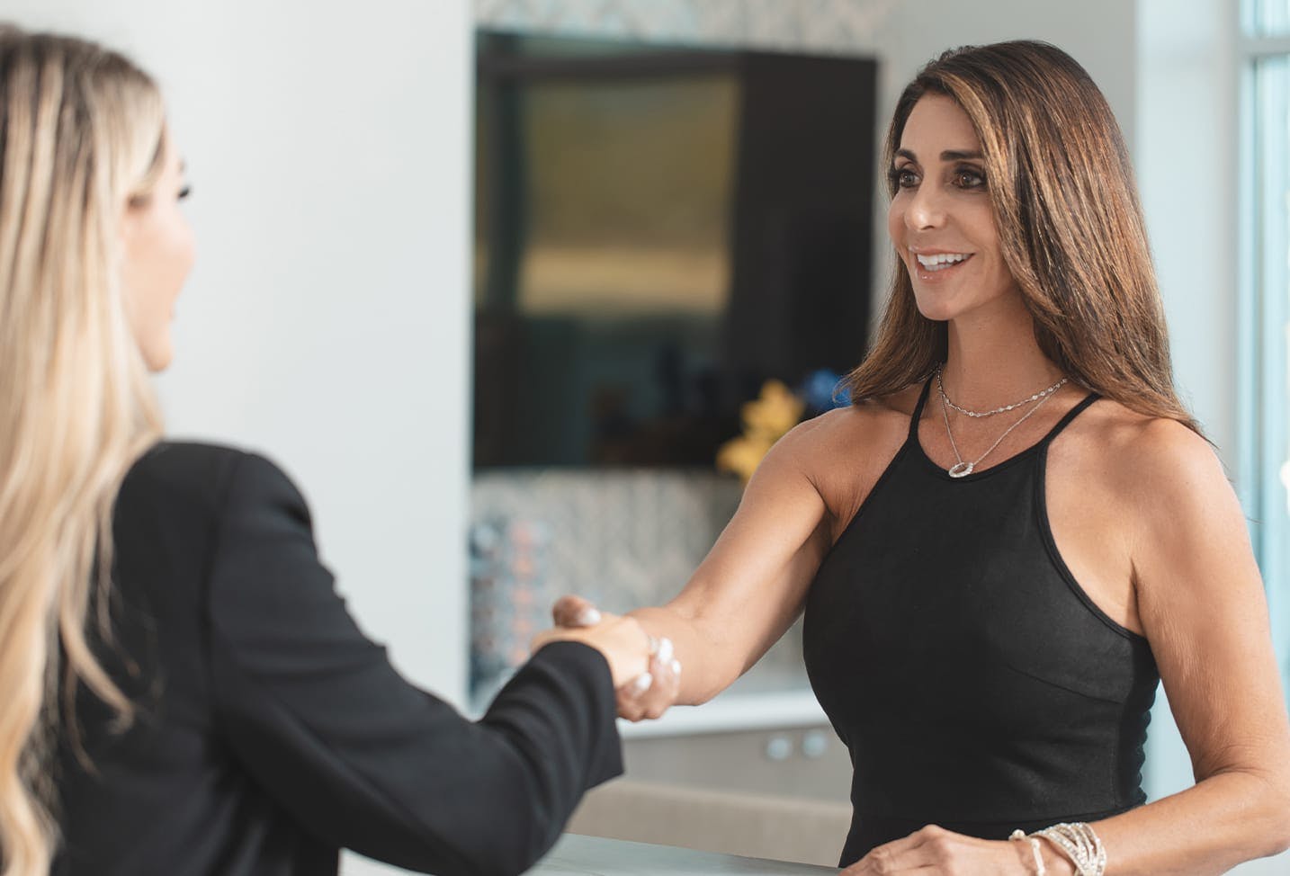 brunette patient giving a woman at the front desk a handshake