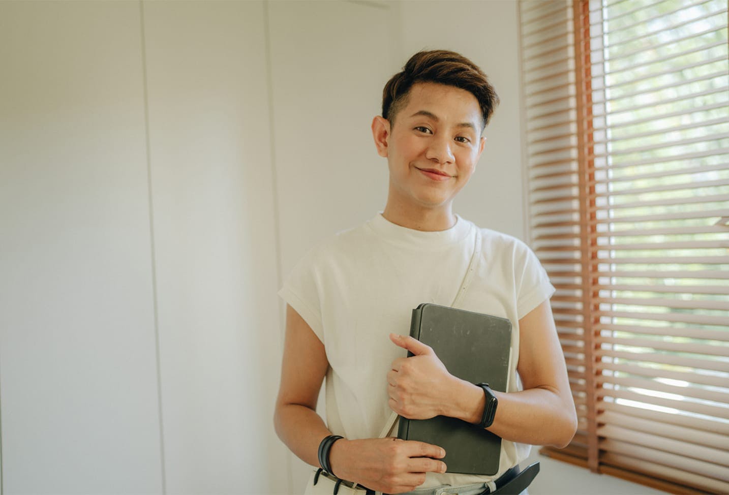 a model with short brunette hair in a white shirt holding a tablet