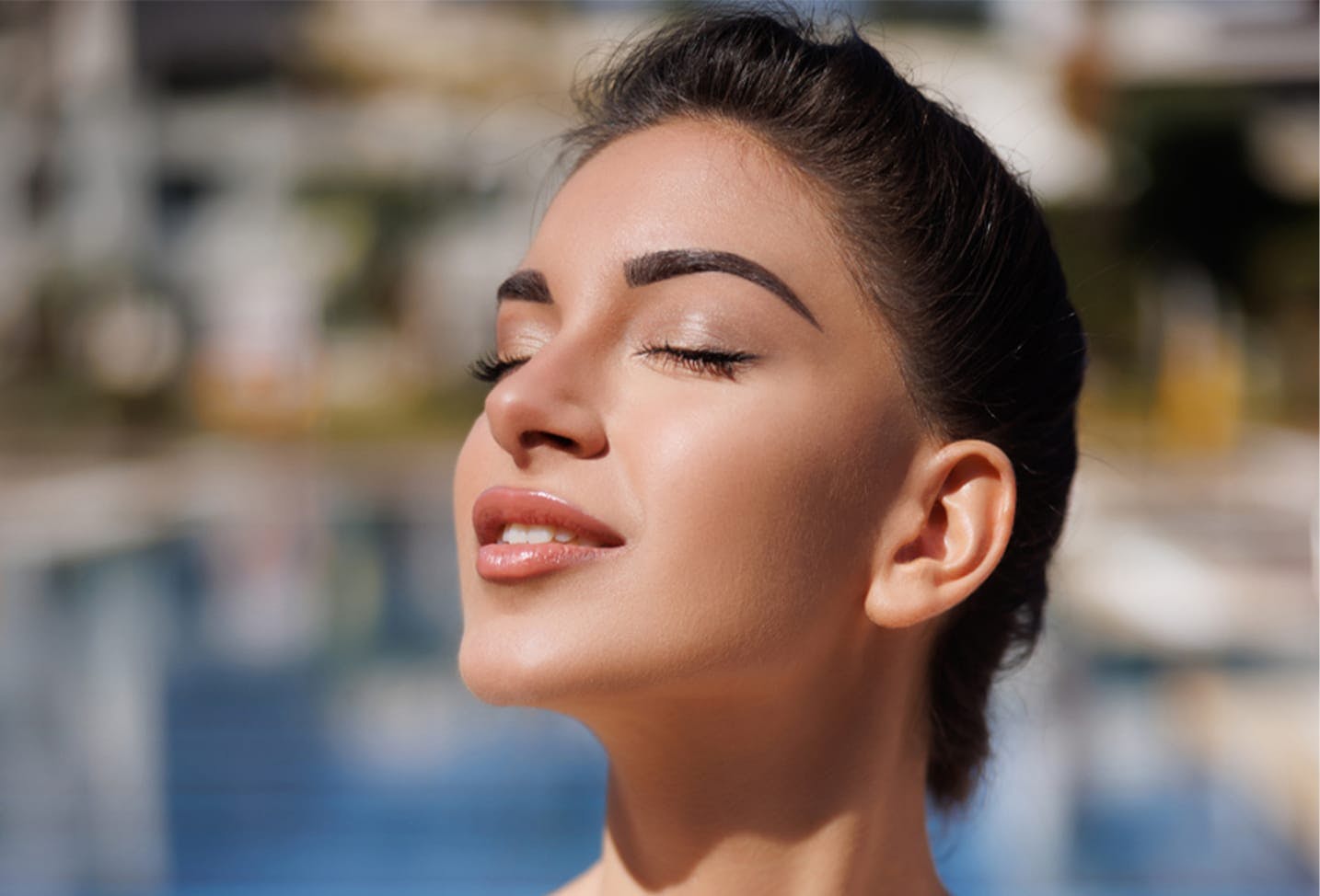 a female model with dark hair in a bun basking in the sun