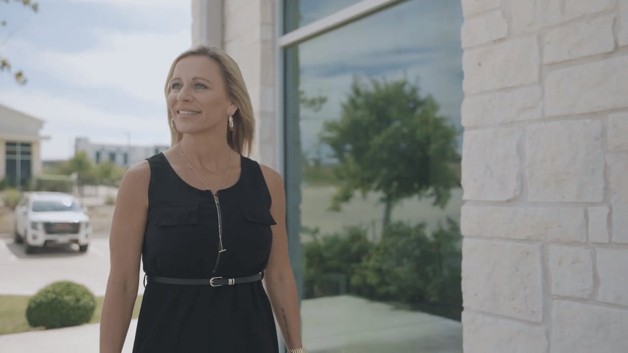 a still of a woman with short blonde hair standing outside of the ACS building