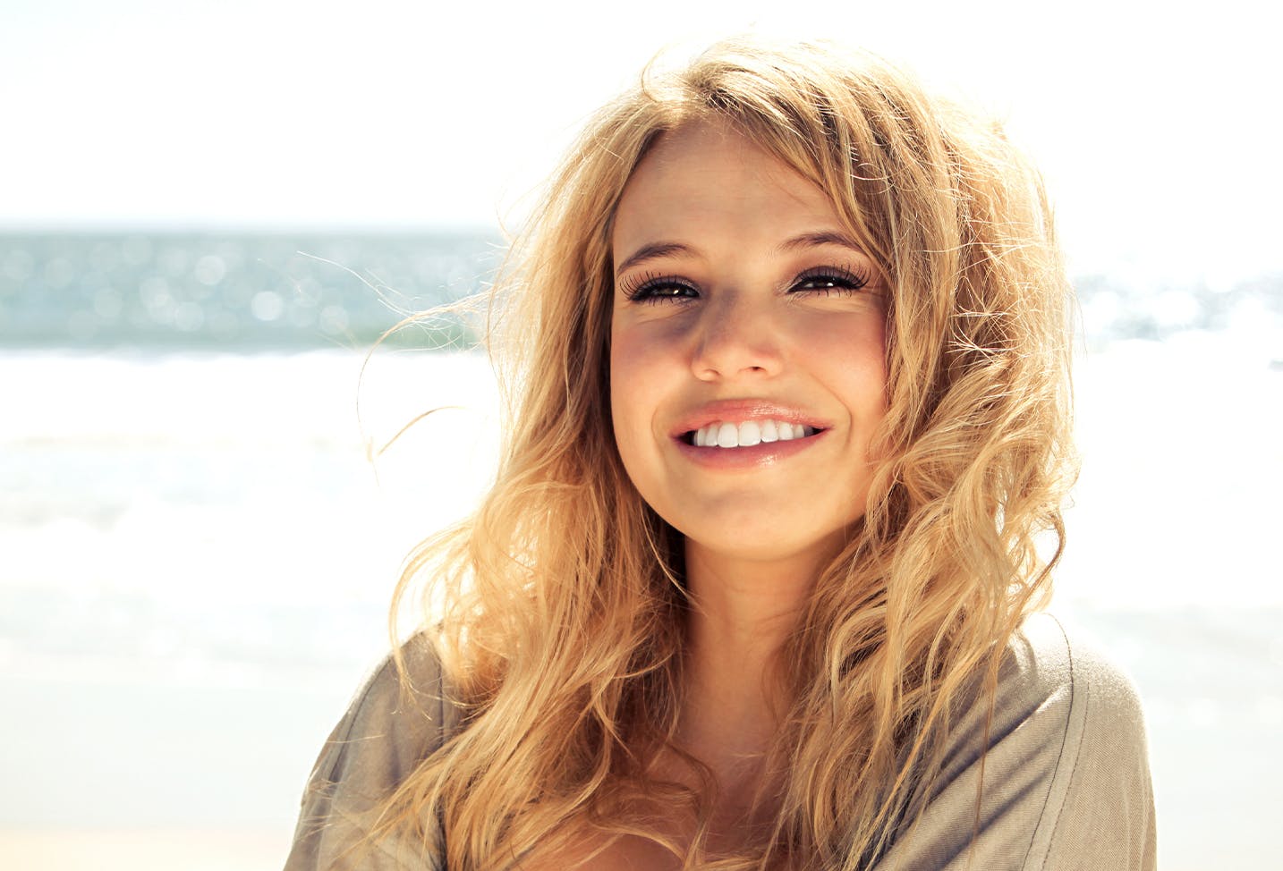 A blonde woman smiling on the beach