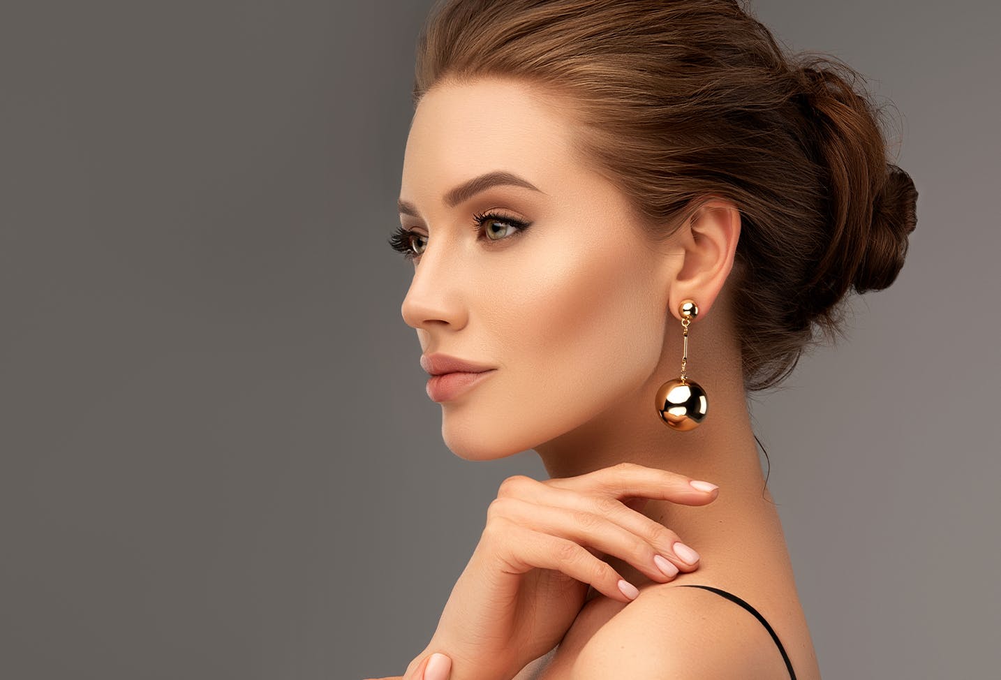 a profile image of a woman with brunette hair wearing a hanging gold earring