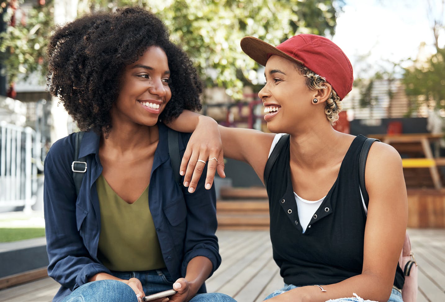 two people sitting on a deck talking and laughing together