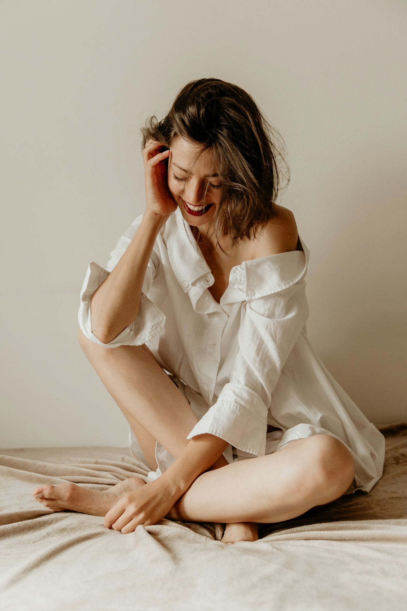 Woman sitting on bed in white button down shirt