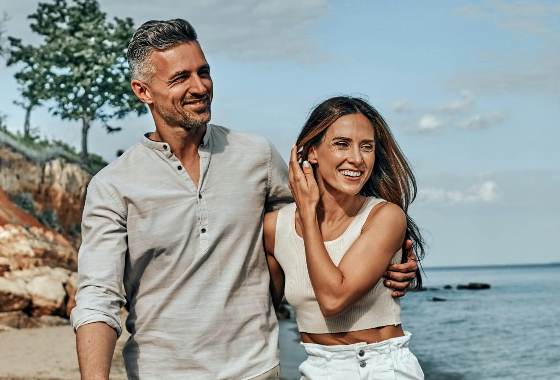 Man and woman smiling while walking by beach