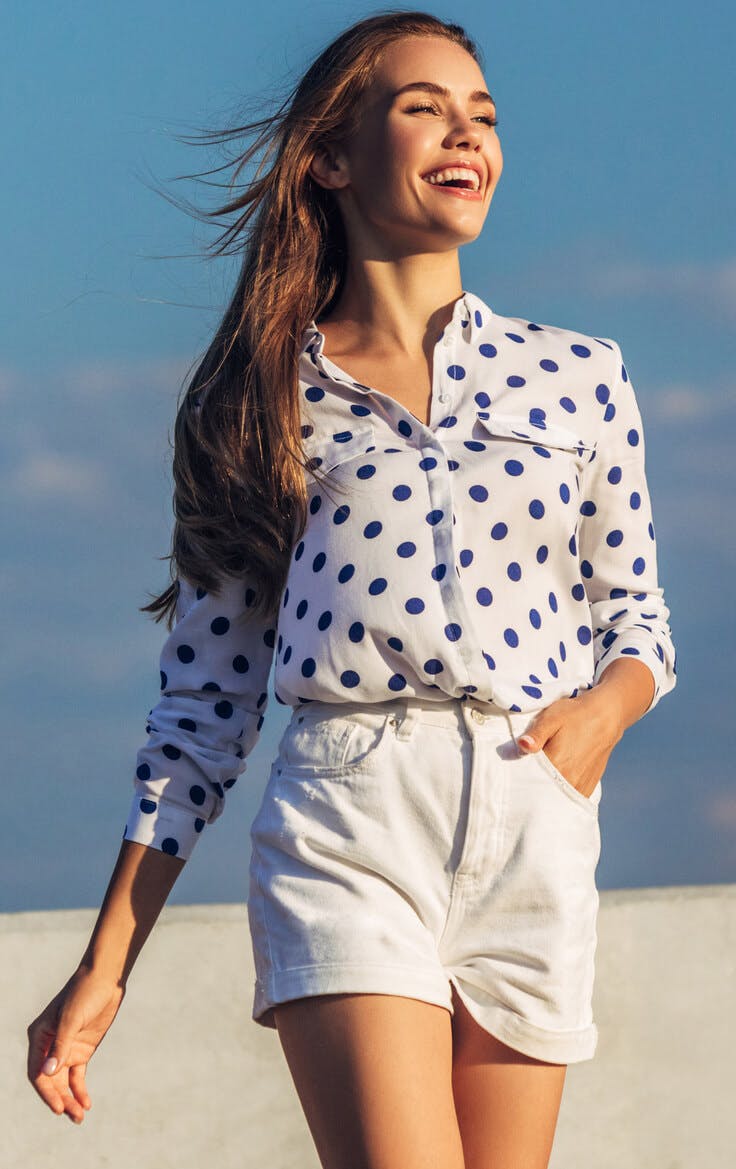 Woman laughing in shorts and blouse on beach