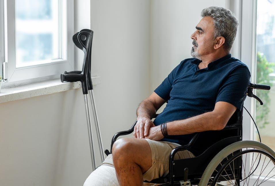 Man in wheelchair looking out of a window