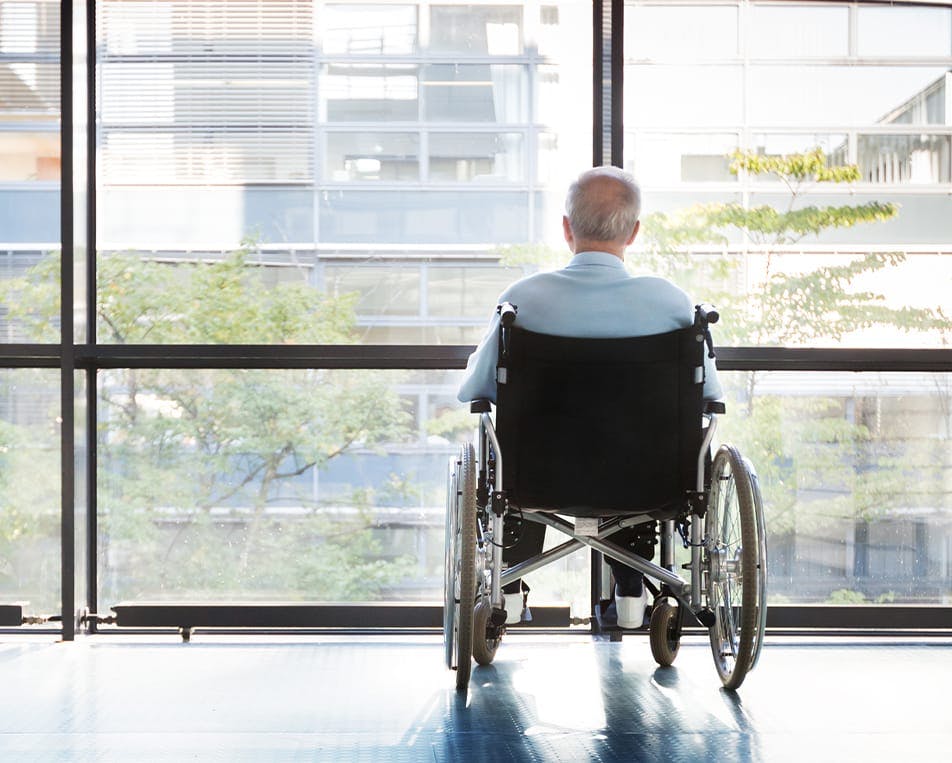 Man in wheelchair looking out a window