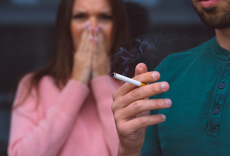 Woman covering her face from cigarette smoke