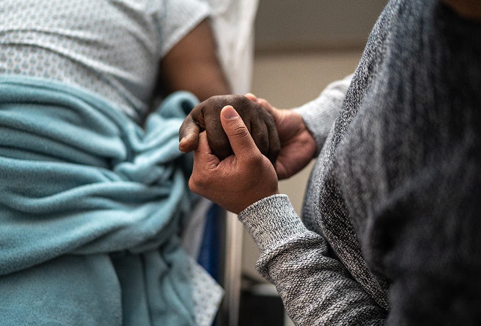 Person holding patient's hand in the hospital