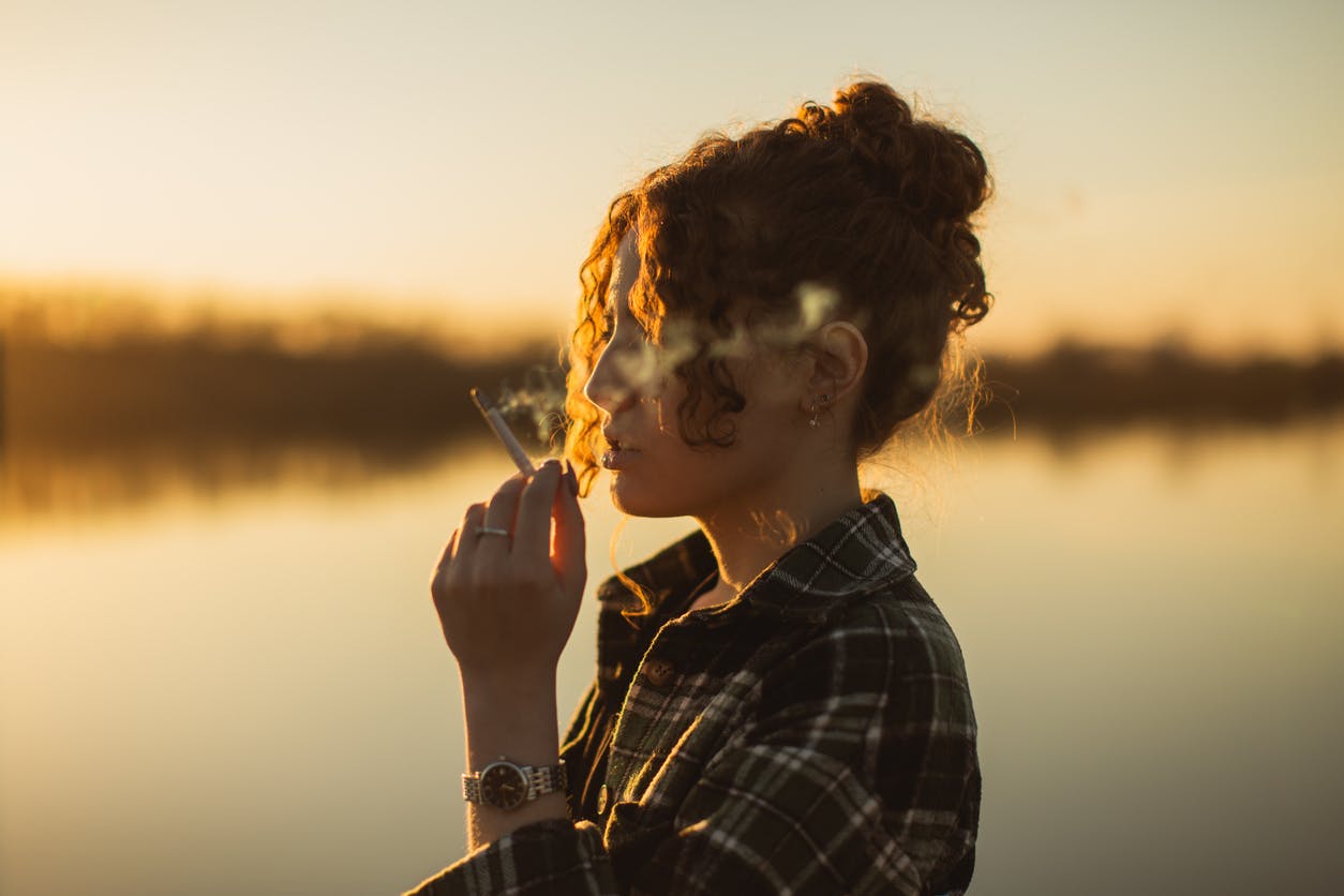 Woman smoking by a lake