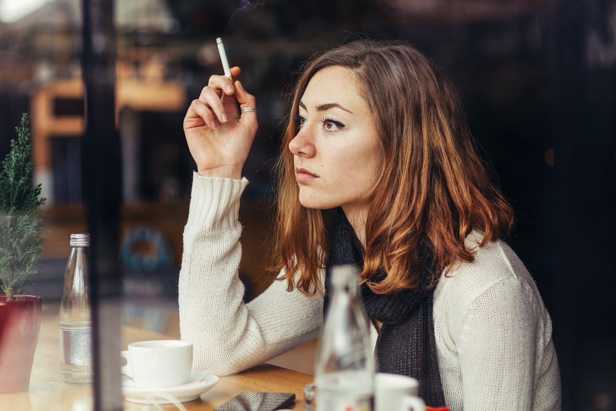 Woman sitting in a coffee shop, smoking