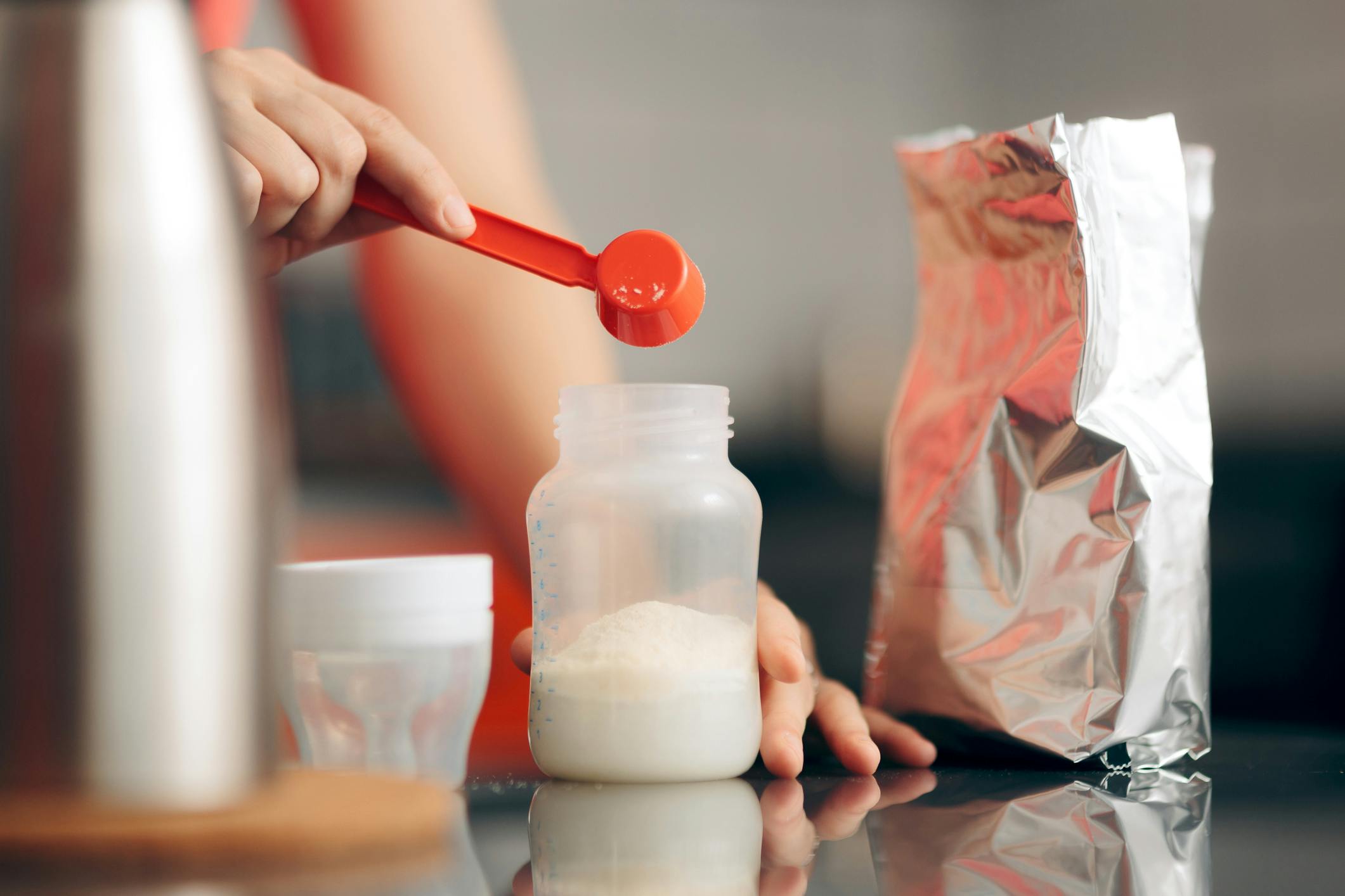 Woman pouring baby formula into a bottle