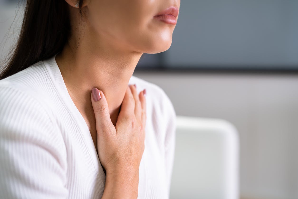 A woman holding her hand up to her throat