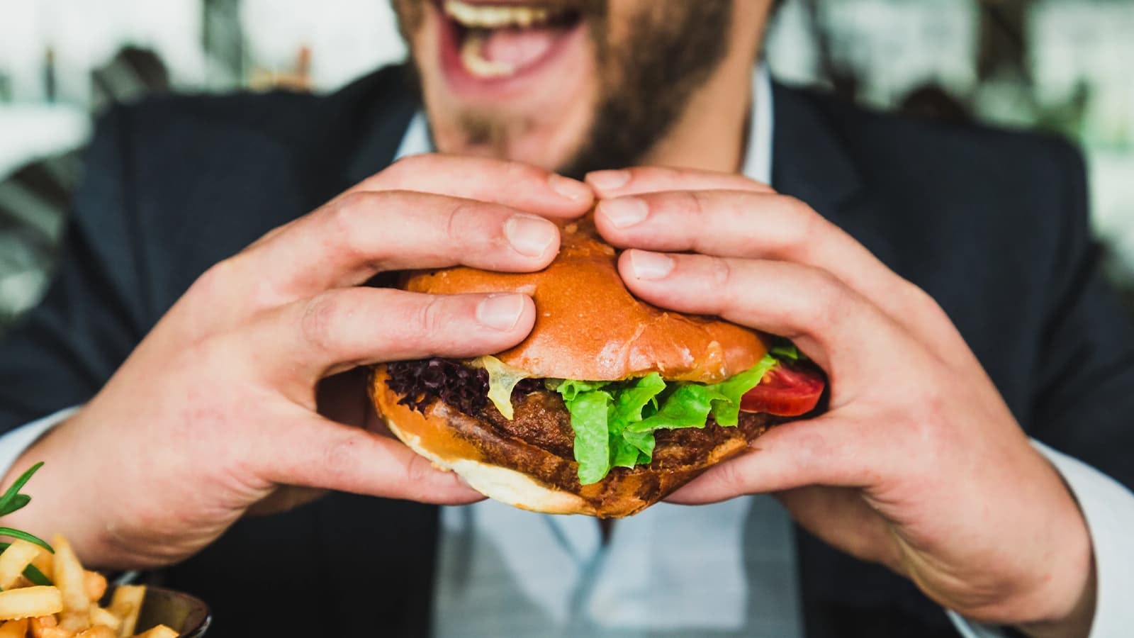 Richtiges Training & Ernährung in der Massephase. Bild mit einem Mann, der während der Massephase einen Burger isst.