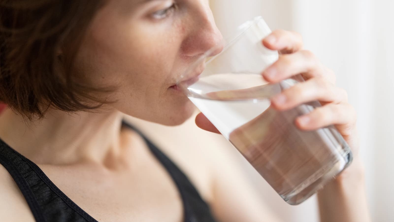 Was ist Intervallfasten? Bild mit einer Frau, die während dem Intervallfasten ein Glas Wasser trinkt.