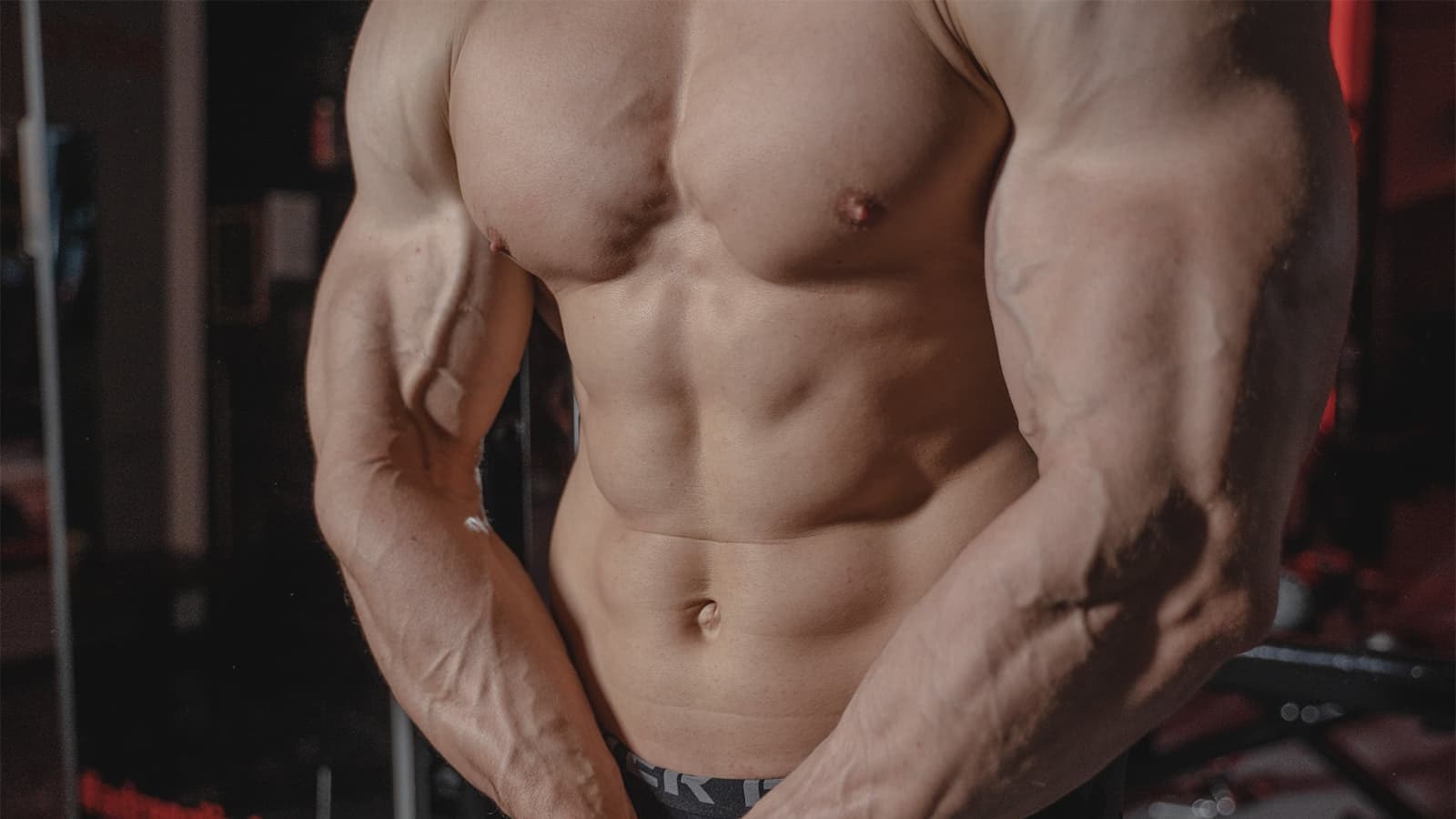 Was ist Hypertrophie? Bild mit einem Mann, der seine Muskeln anspannt, welche aufgrund der Hypertrophie gewachsen sind.