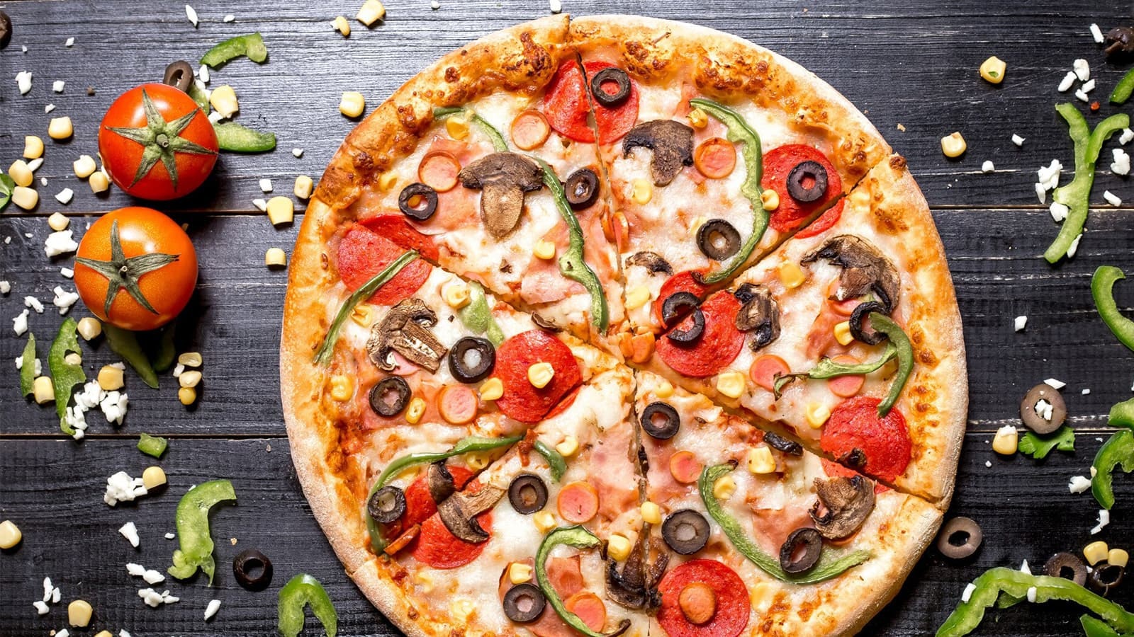 Die perfekte Low Carb Pizza backen. Bild von einer Low Carb Pizza und Zutaten auf einem Holztisch.