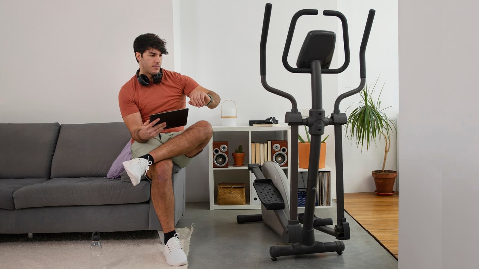 Die besten Sportgeräte für Zuhause. Bild von einem Mann neben einem Crosstrainer, welches eines der beliebtesten Sportgeräte für Zuhause ist.