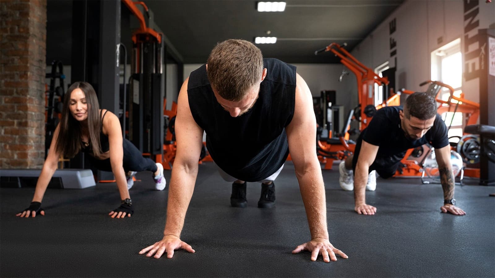 Wie macht man Burpees richtig? Bild von drei Sportlern, die Burpees ausführen.