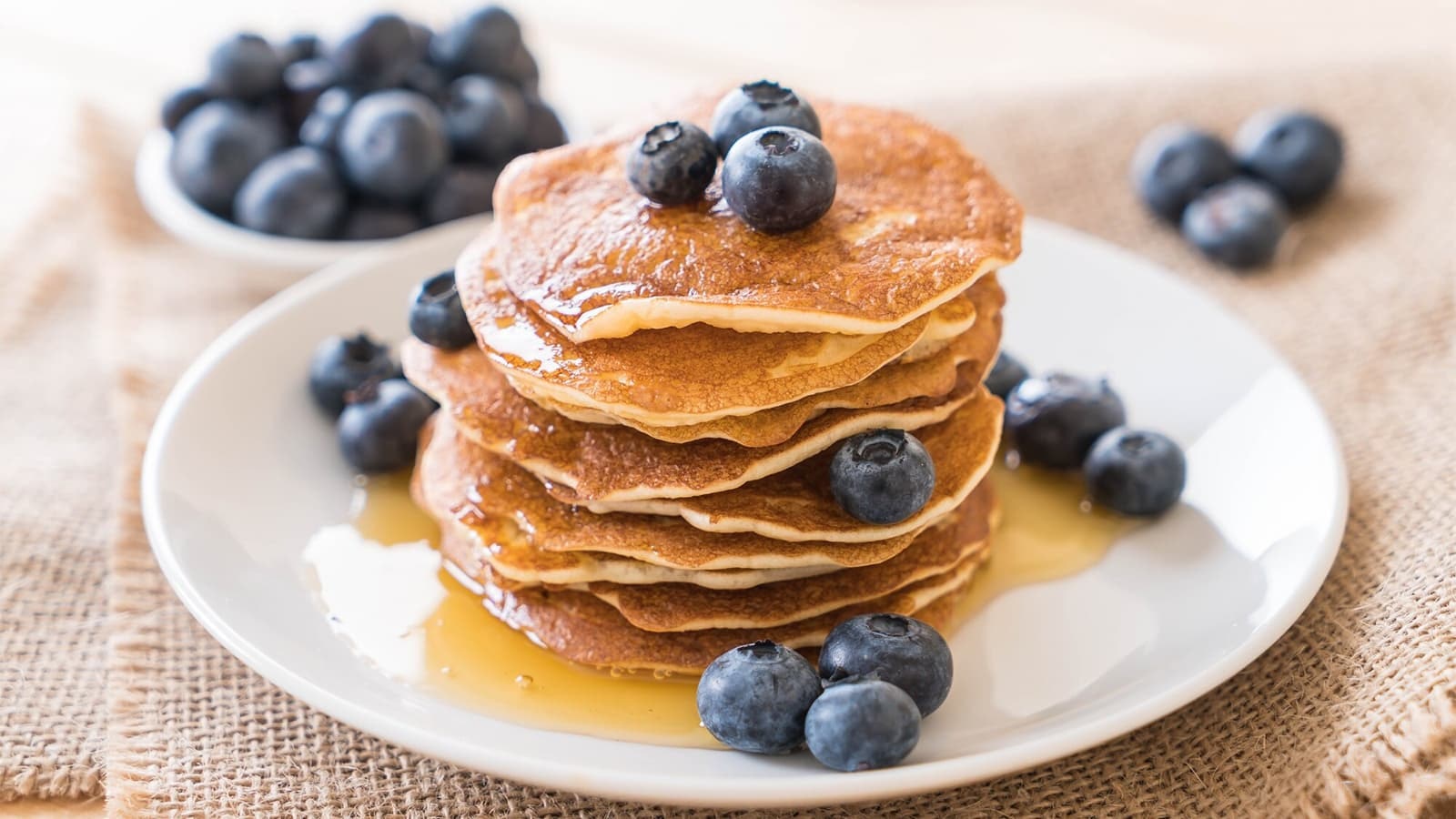High Protein Pancakes auf einem Teller mit Blaubeeren und Honig.