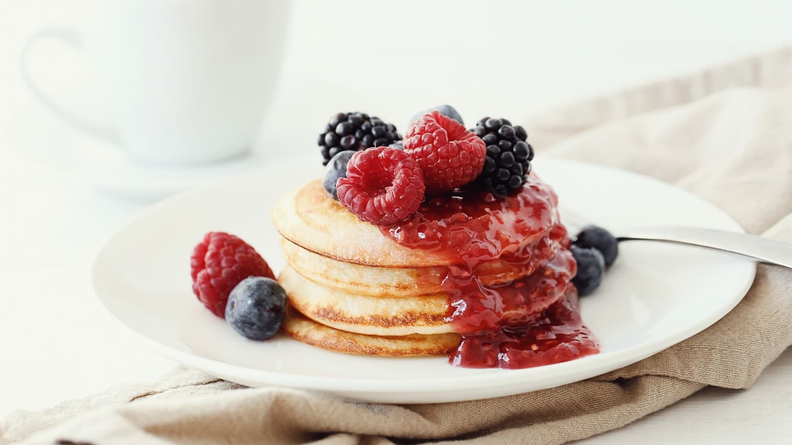 Protein Pancakes auf einem Teller mit verschiedenen Beeren.