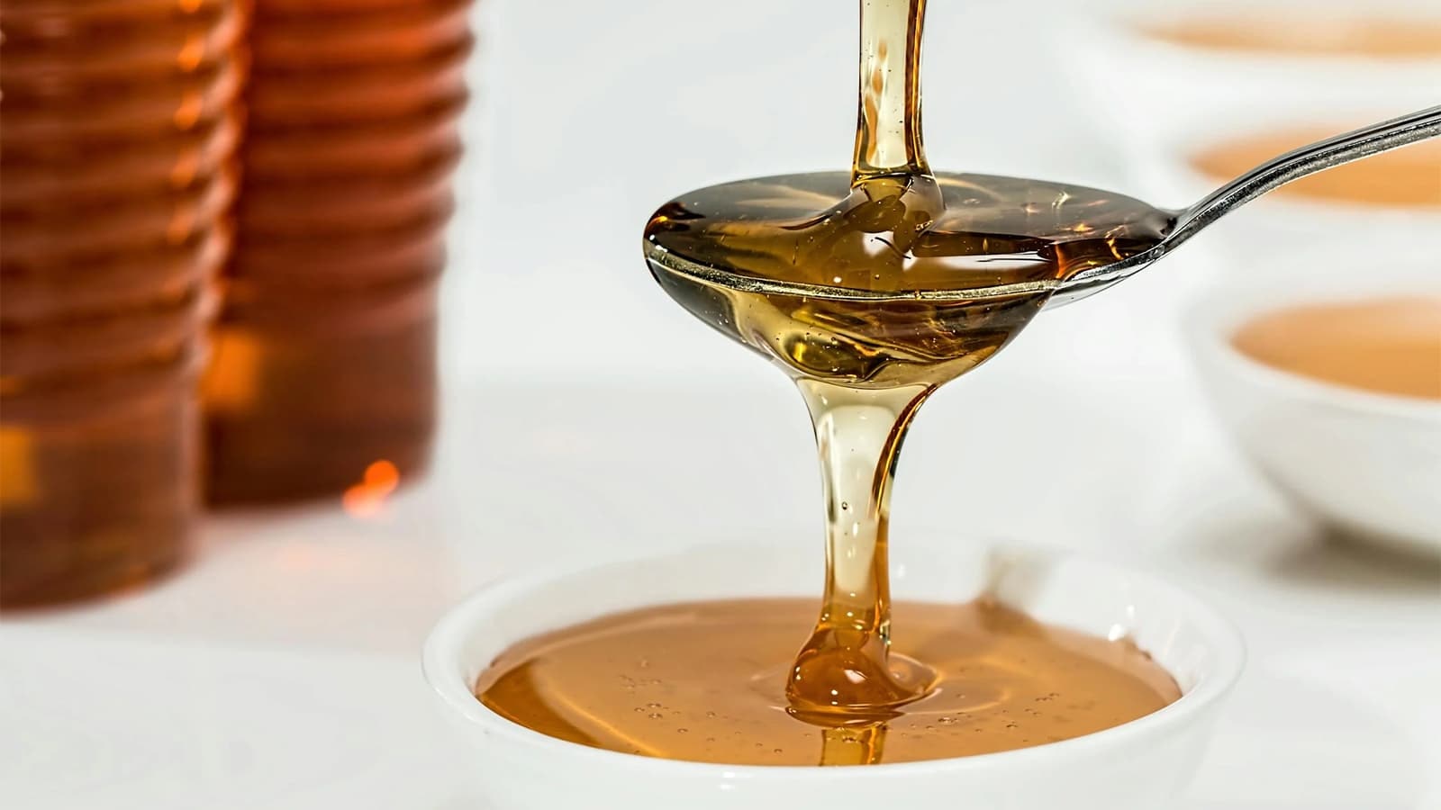 Ist Agavendicksaft gesund? Bild von einer Schüssel und einem Löffel, über den Agavendicksaft läuft.