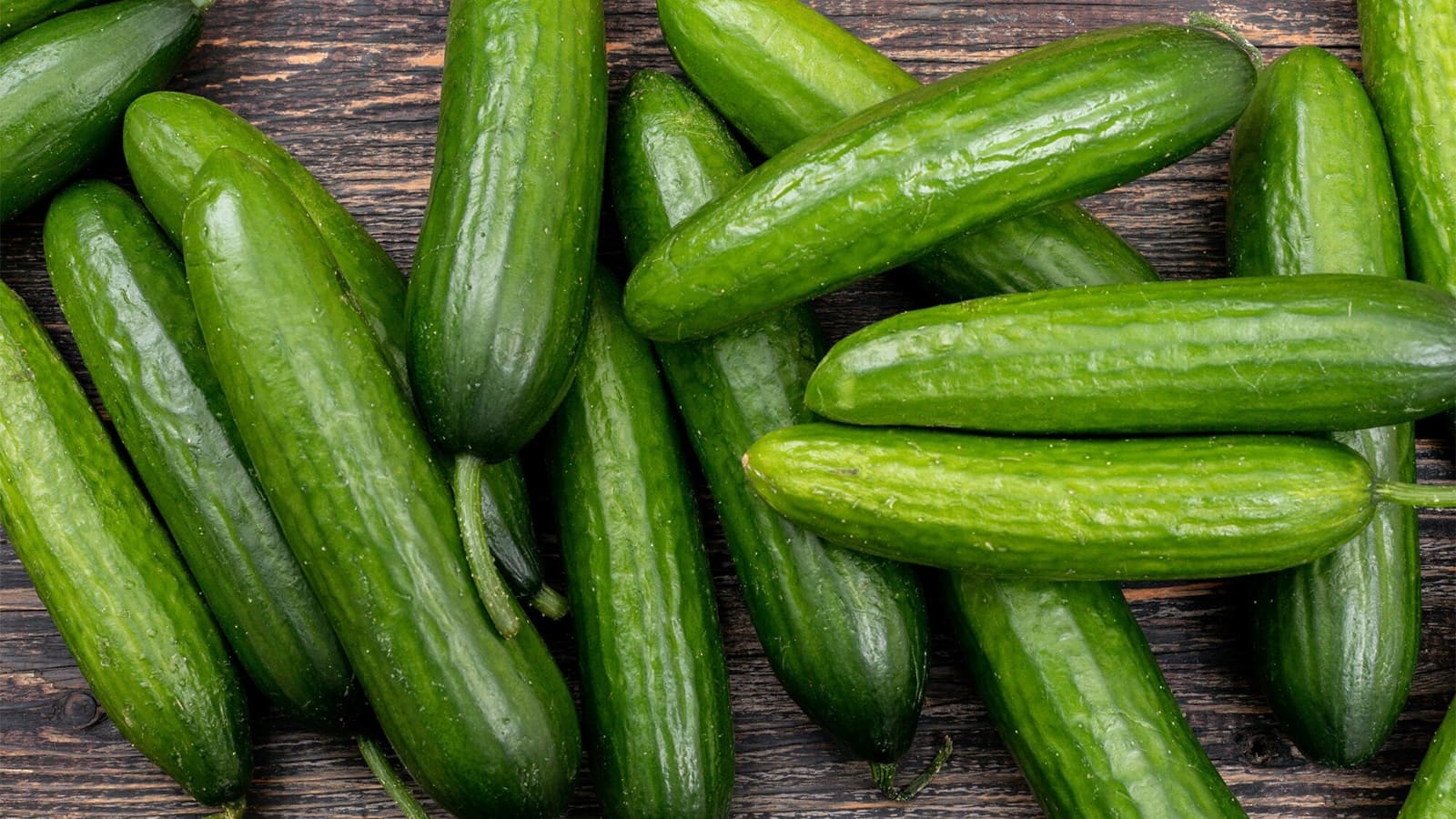 Wie viele Kalorien haben Gurken? Bild von mehreren Gurken, die auf einem Holzbrett liegen.