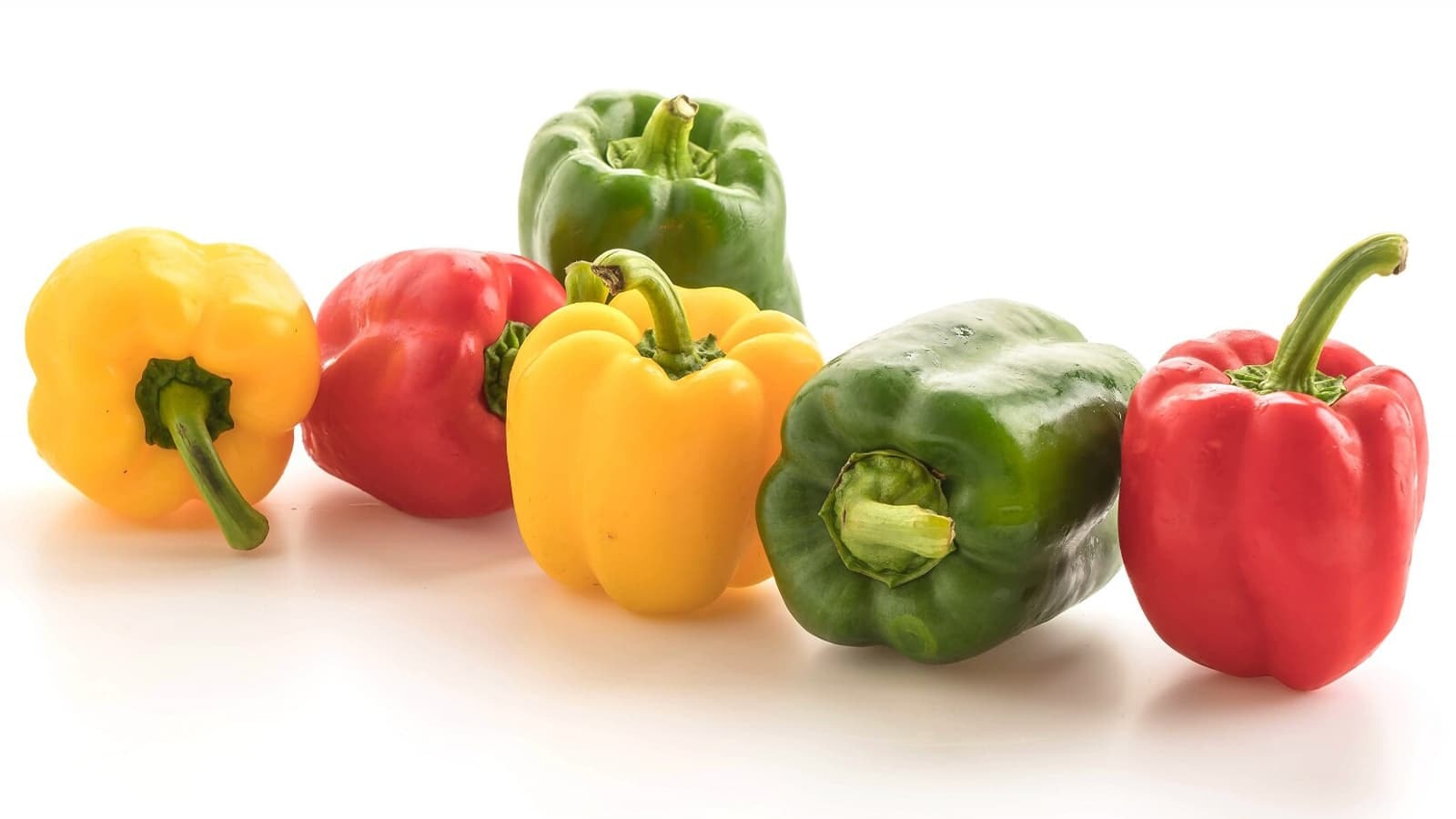 Wie gesund ist eine Paprika? Bild von mehreren Paprikas vor einem weißen Hintergrund.
