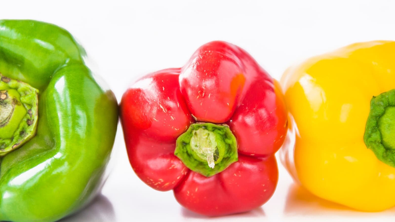 Wie gesund ist eine Paprika? Bild von mehreren Paprikas vor einem weißen Hintergrund.
