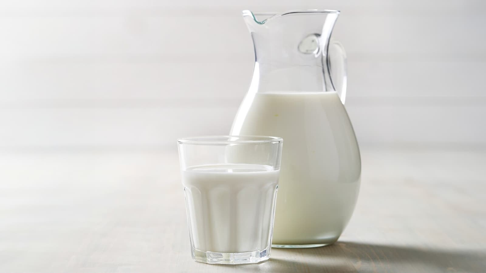 Die Wahrheit über Milch: Gesund oder schädlich? Bild von einem Glas und einer Kanne voll mit Milch.