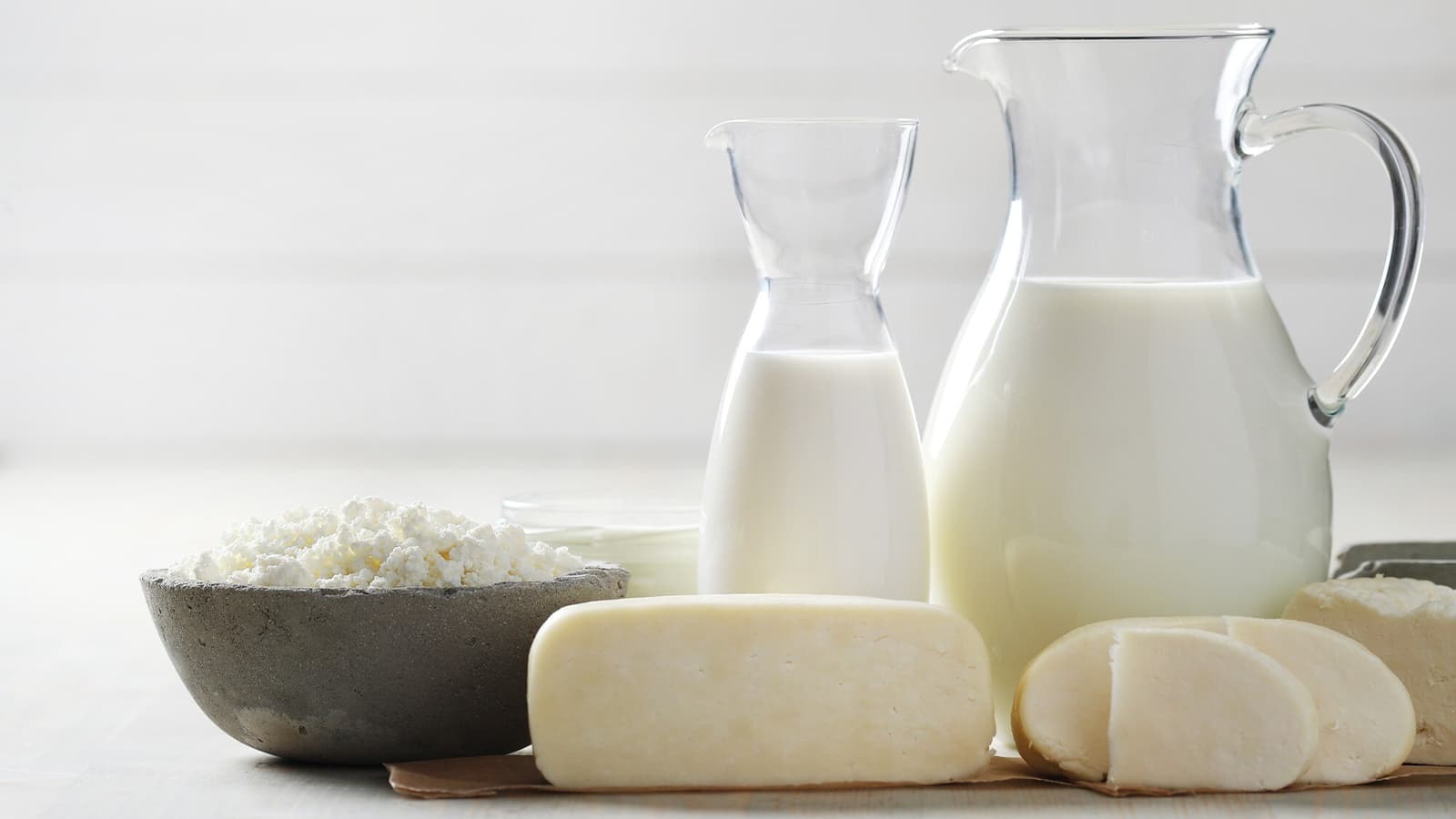 Die Wahrheit über Milch: Gesund oder schädlich? Bild von einer Kanne mit Milch neben anderen Milchprodukten.