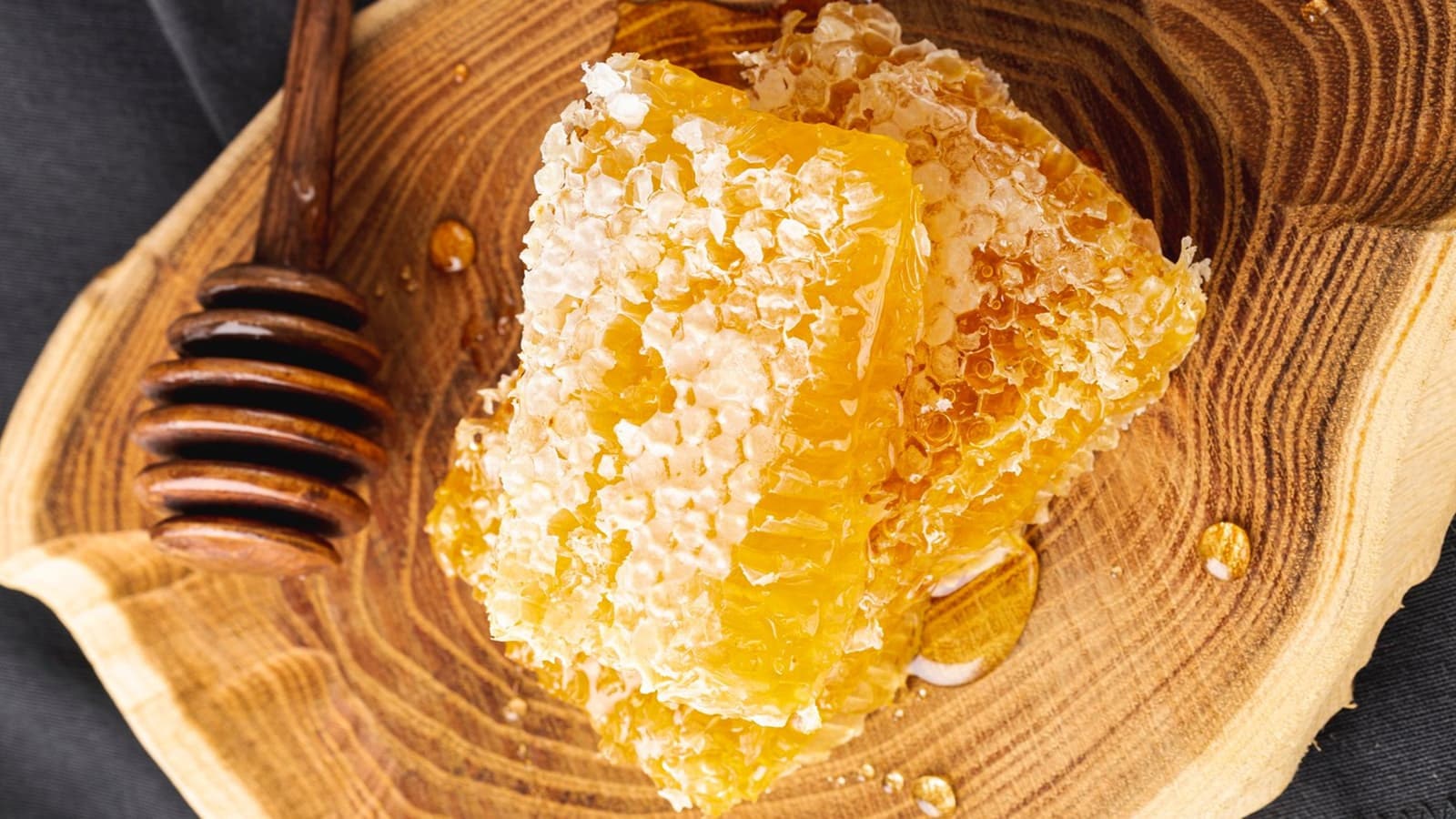 Wie gesund ist eigentlich Honig? Bild von einer Bienenwabe mit Honig auf einem Holzbrett.