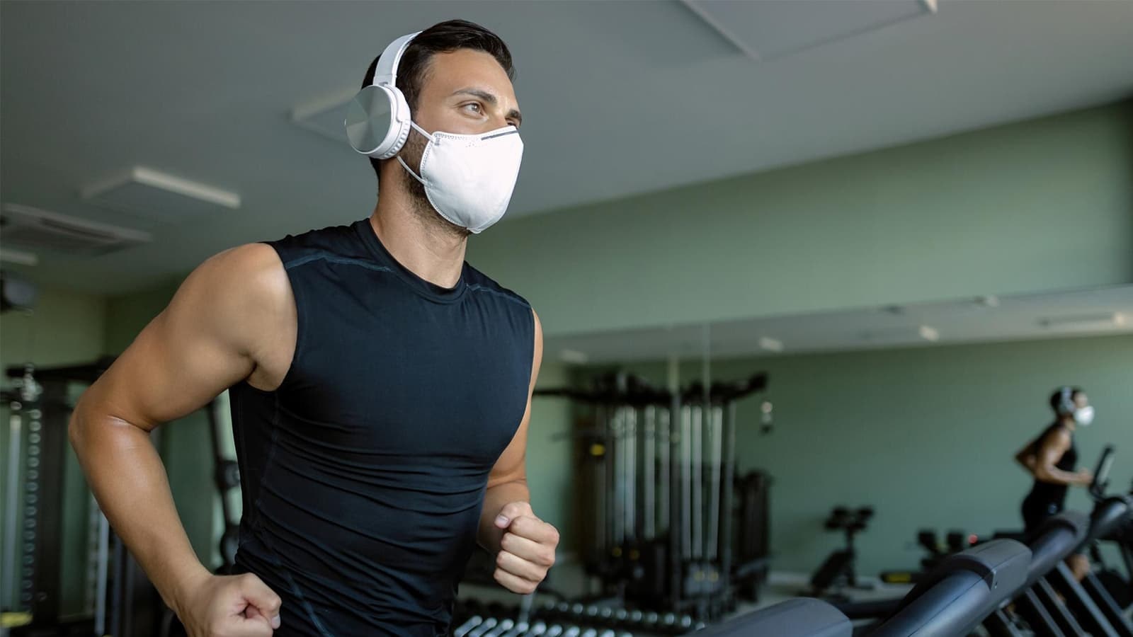 Ein Mann mit Kopfhörern und einer Maske auf einem Laufband.
