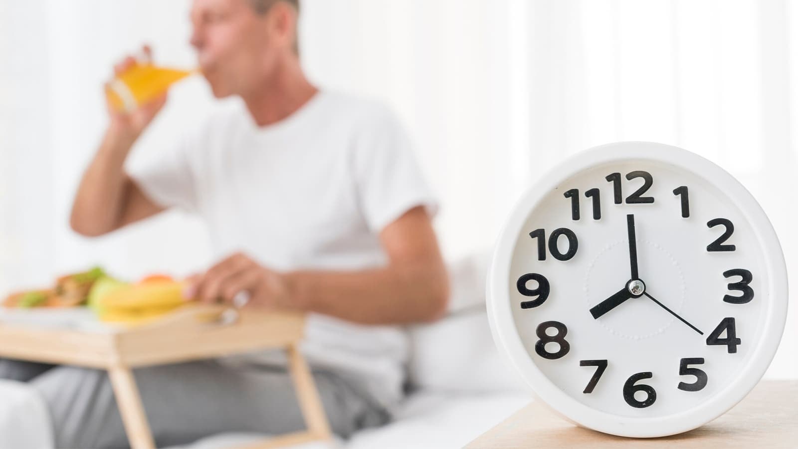 Eine Uhr im Vordergrund und ein trinkender Mann im Hintergrund.