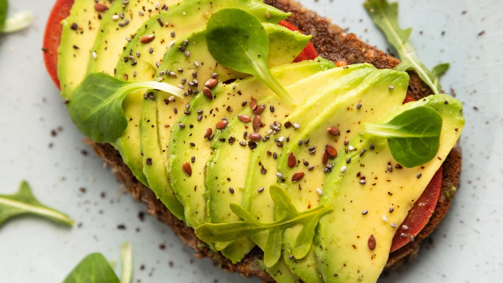 Ein Stück Brot belegt mit Avocado und Tomaten.
