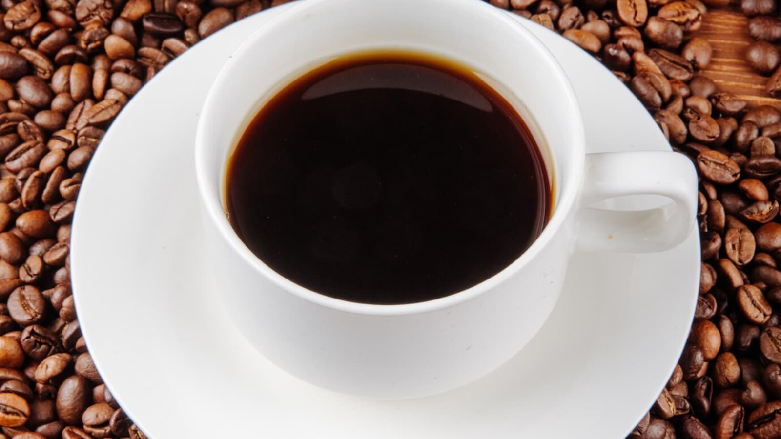 Eine Tasse Kaffee auf einem Haufen an Kaffeebohnen