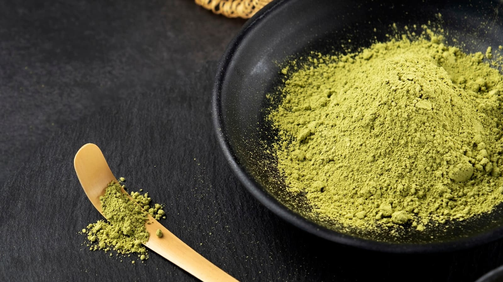 Eine dunkle Schale voll mit grünem Matcha-Pulver.