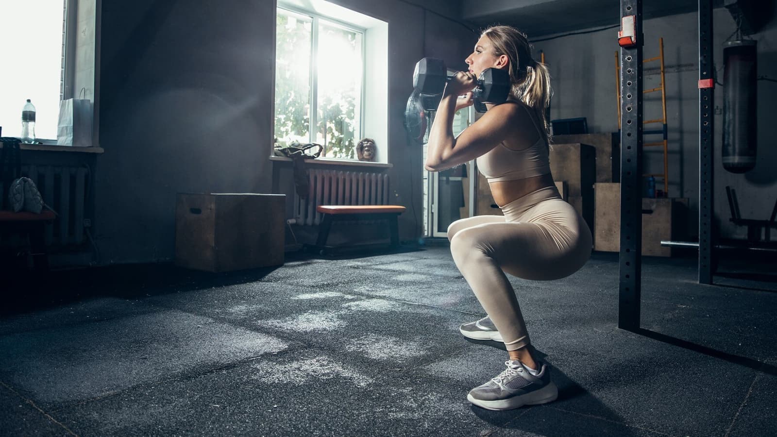 Eine Frau, die Squats mit zwei Kurzhanteln in den Händen durchführt.