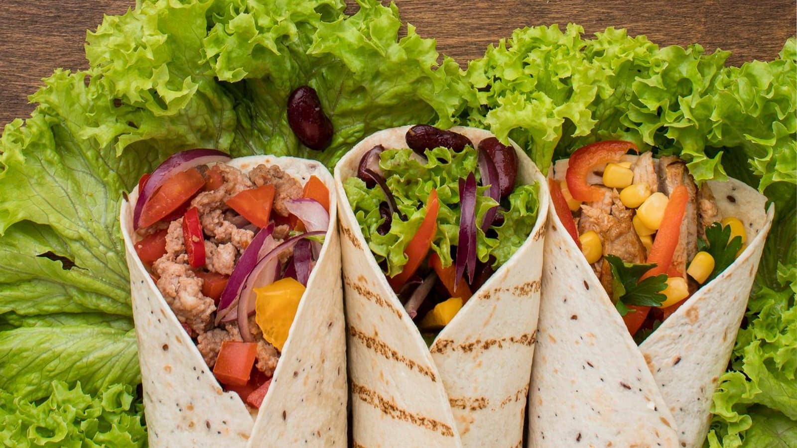 Drei Protein Burritos auf einem großen Salatblatt.
