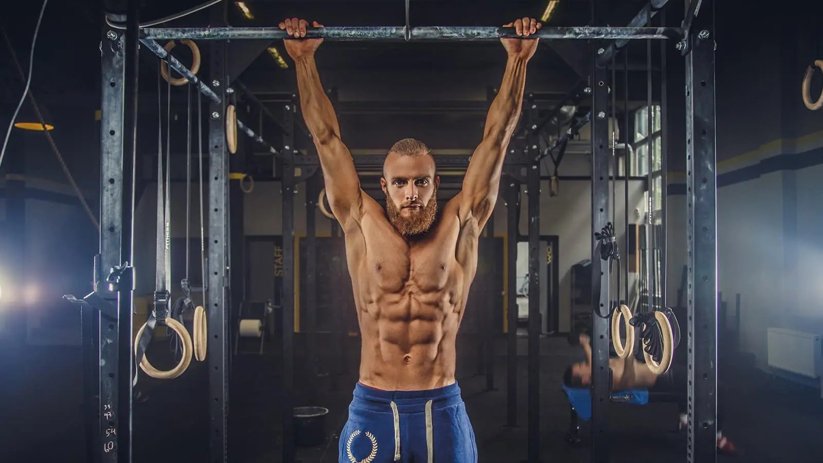 Bild von einem Mann mit Sixpack, der an einer Klimmzugstange hängt.