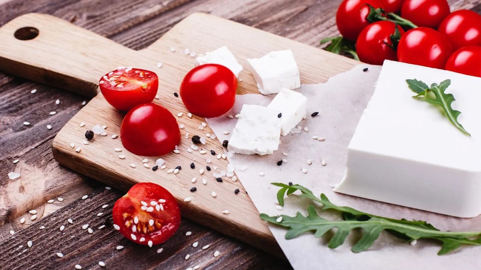 Ein Schneidebrett, auf dem sich Tomaten und Feta befinden.