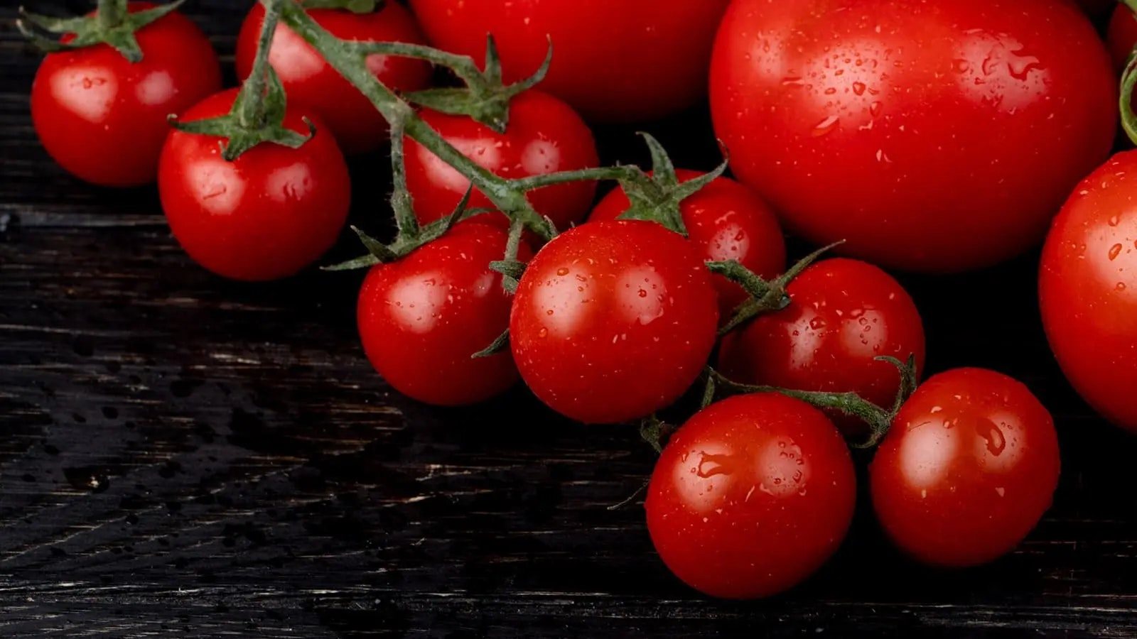 Mehrere Tomaten auf einem dunklen Holzboden.