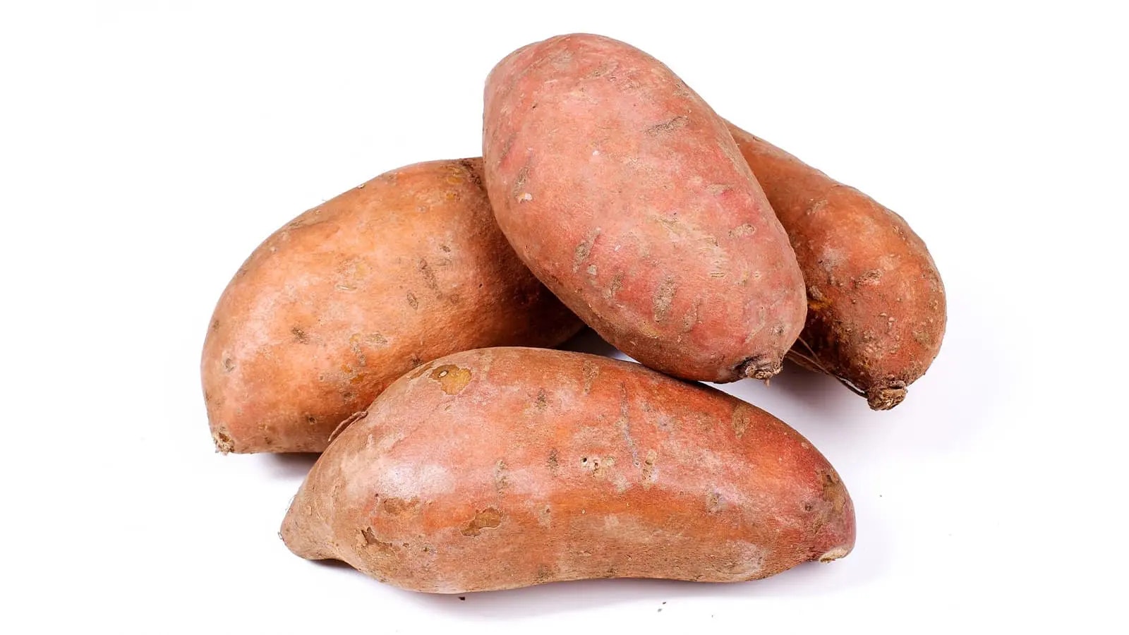 Mehrere Süßkartoffeln vor weißem Hintergrund.