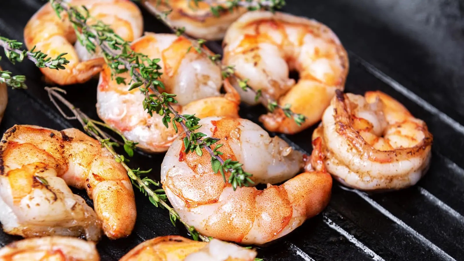 Garnelen und Kräuter auf einem Grill.