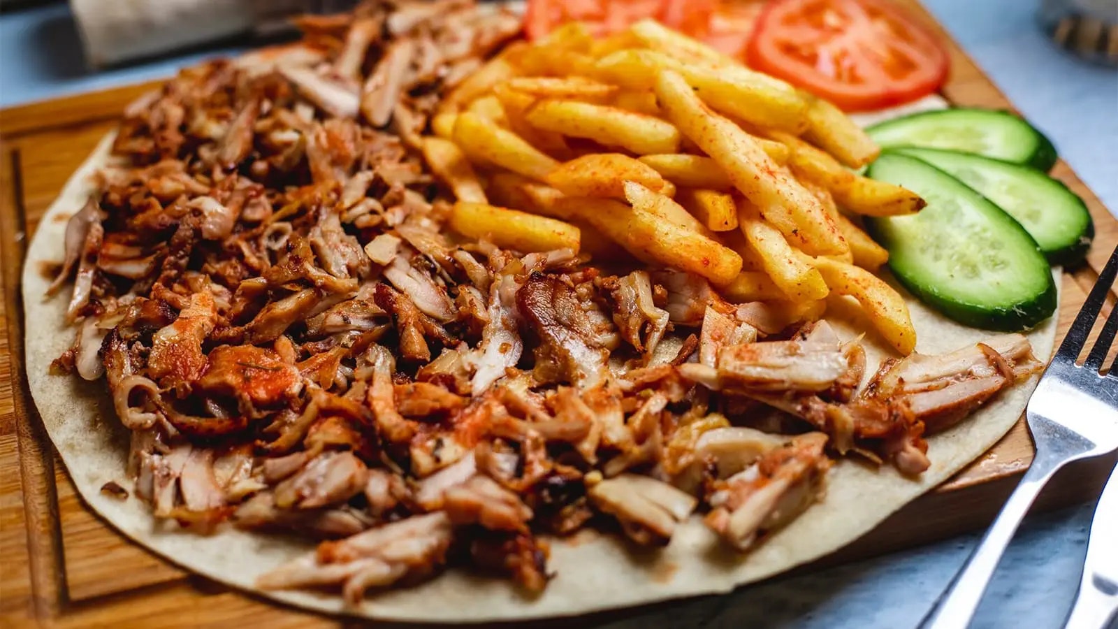 Dönerfleisch, Pommes und Gemüse auf einem Fladenbrot.